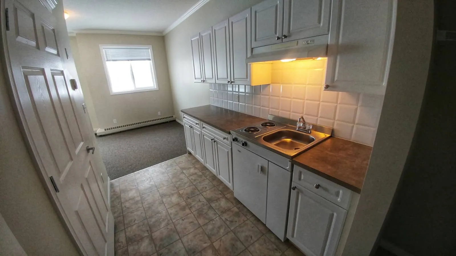 A suite galley kitchen with white cabinets